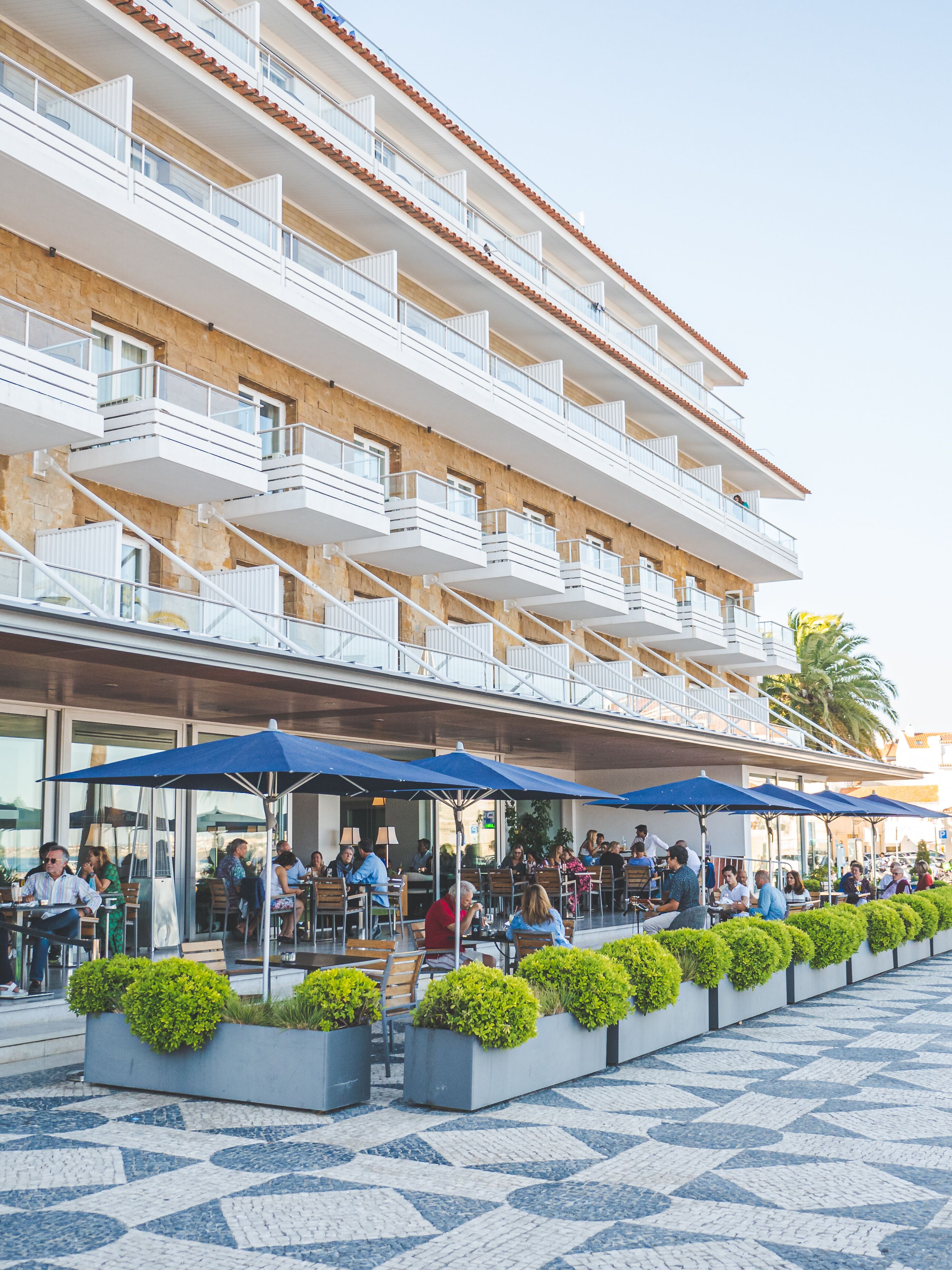 Un hotel con terraza, varios balcones y suelo de baldosas.