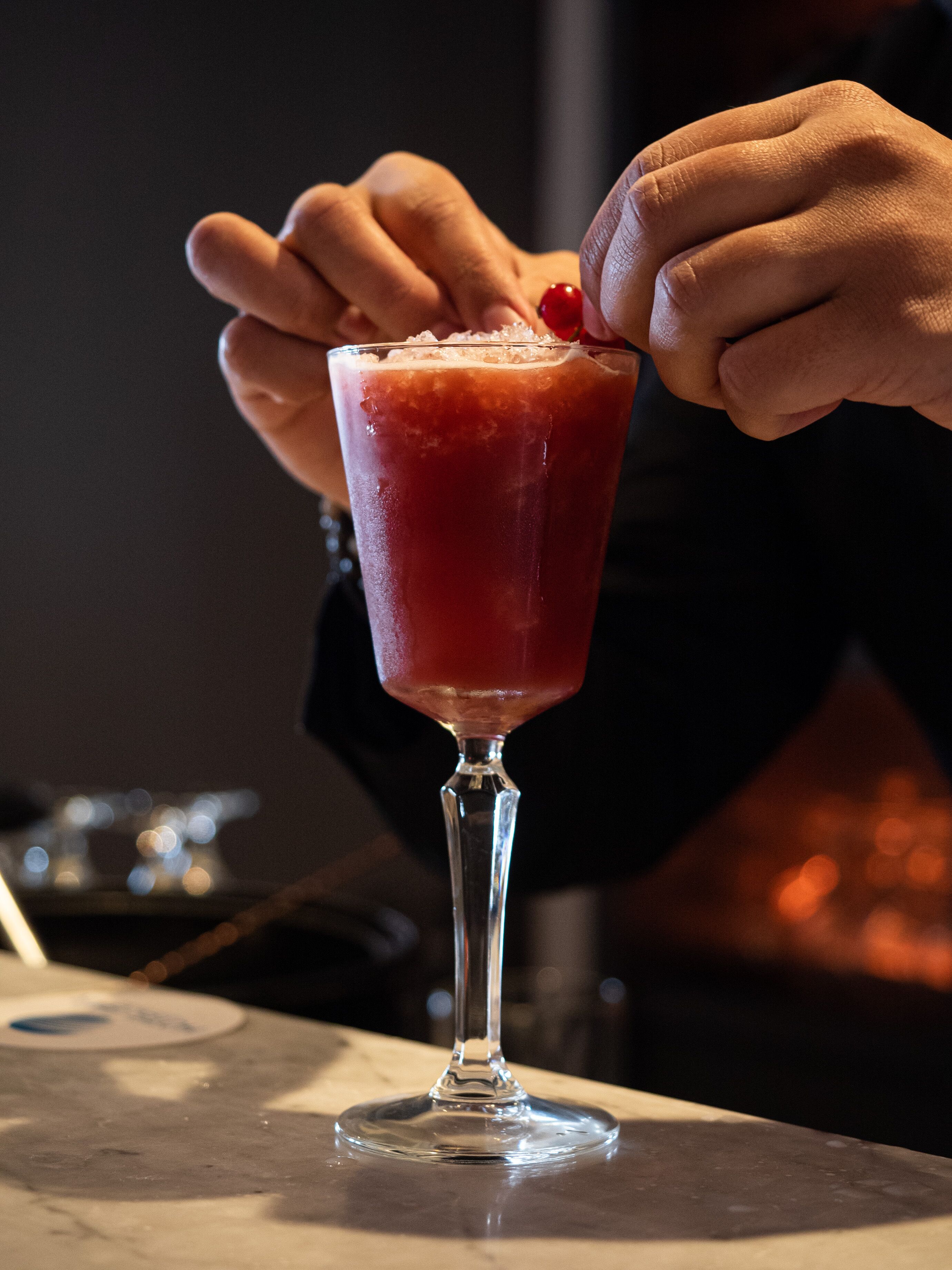 Ein Cocktail im Stielglas mit einer Kirsche als Garnitur.