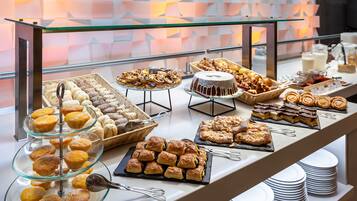Un bufé con diversos pasteles y postres exhibidos en estantes y platos de vidrio.
