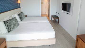 Ein modernes Hotelzimmer mit zwei Betten, einem Fernseher und Holzboden.