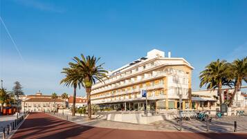 A multi-story hotel with a prominent 'P' parking sign, palm trees, and a red pathway.