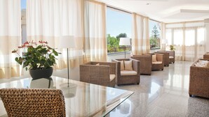 A spacious hotel lobby with a glass coffee table, wicker sofas, and a potted plant. - Hotel Setar (Quartu Sant'Elena)