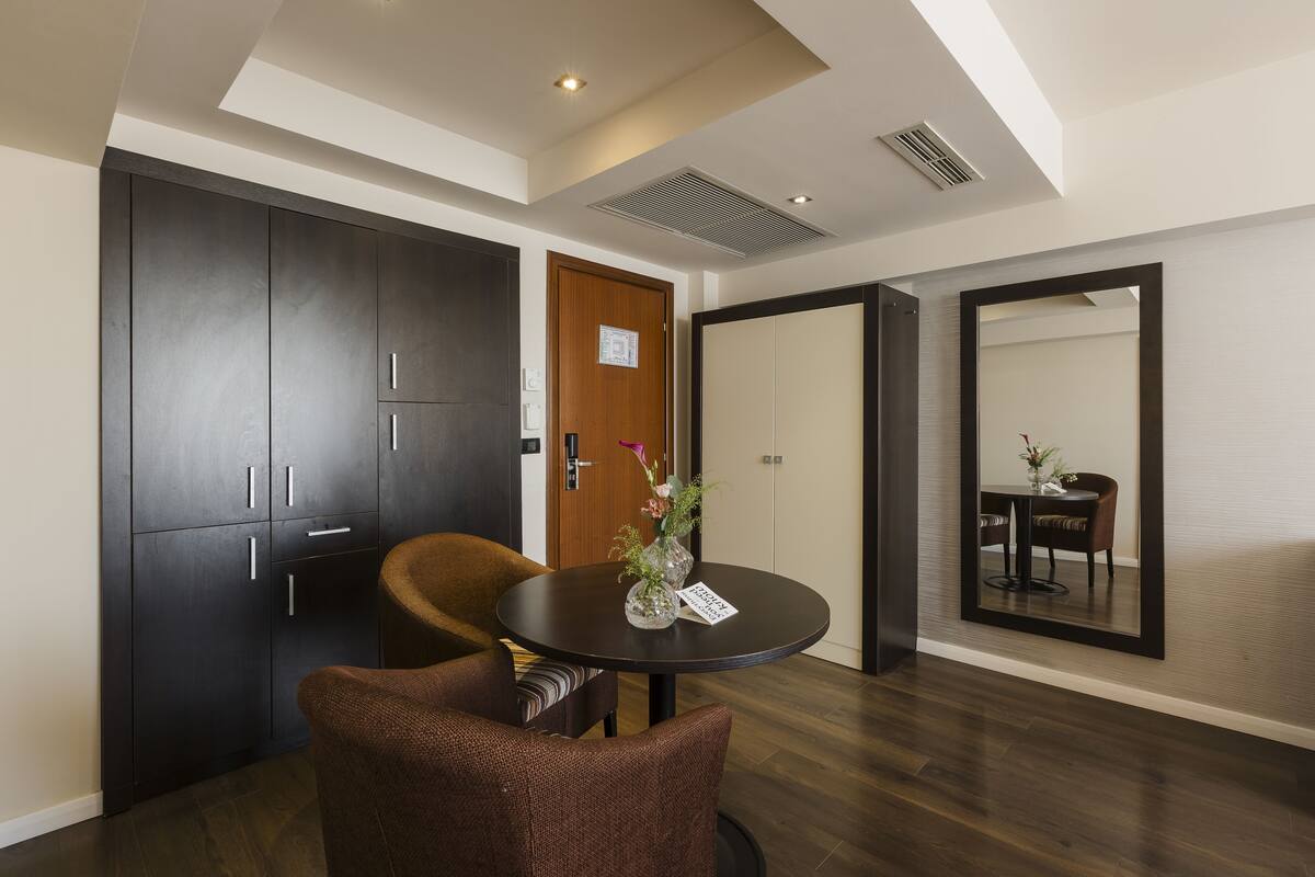 Quarto moderno com uma mesa de jantar, duas cadeiras, um armário de madeira escura e um espelho na parede.