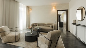 Una sala de estar moderna con un sofá, dos sillones, una mesita de centro y un espejo redondo.