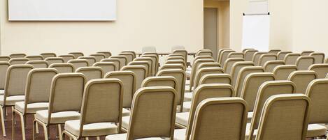A conference room with rows of chairs, a projector screen, and a whiteboard.