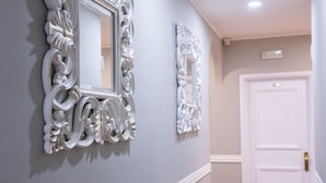 A hallway with ornate white wall mirrors and a white door. - Residenza Florentia (Florence)
