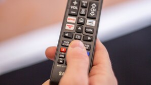 A hand holding a remote control with various buttons and a volume button. - Residenza Florentia (Florence)