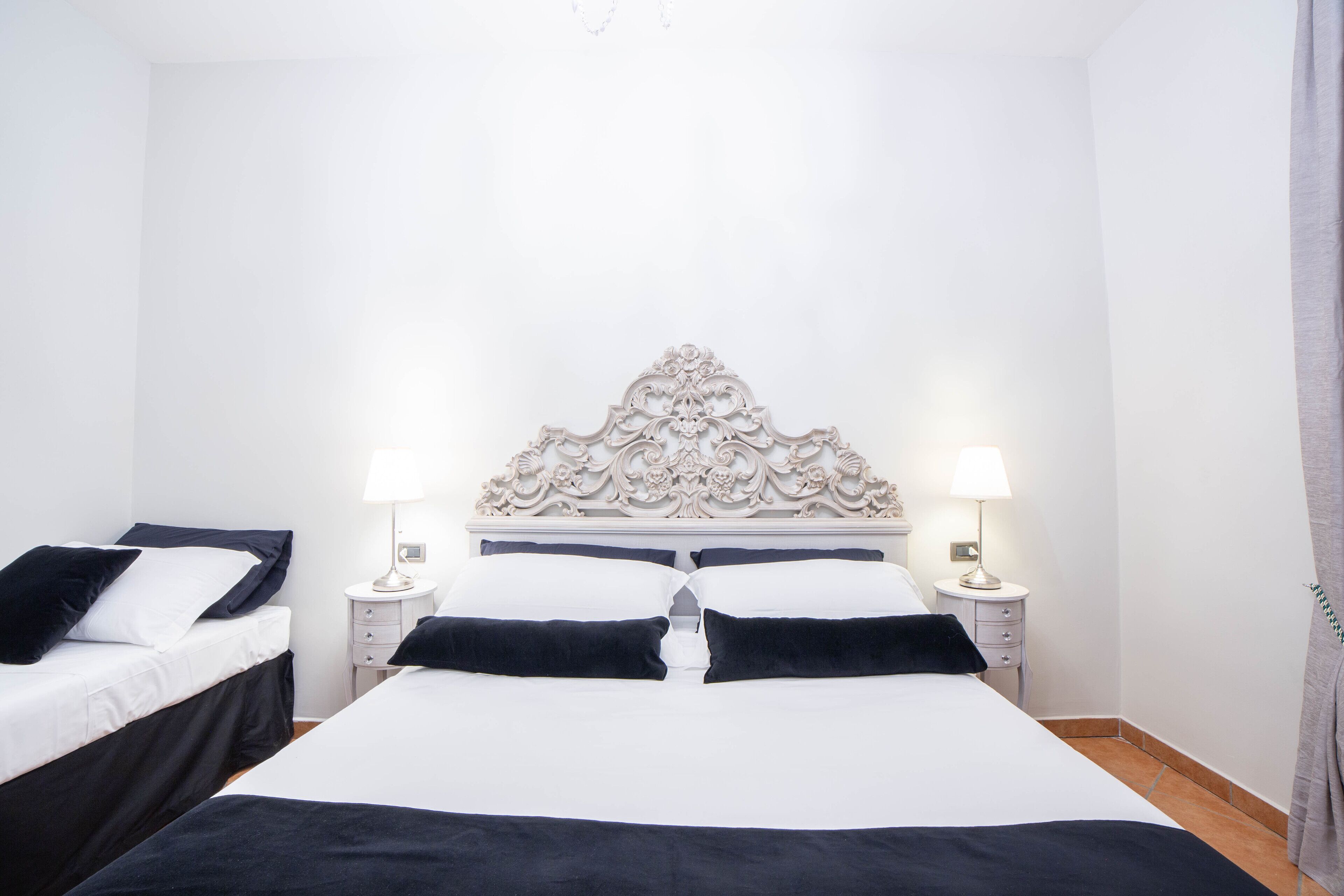 A hotel room with a large bed, two bedside tables, and a decorative headboard.