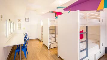 A dormitory room with bunk beds, a desk, and chairs.