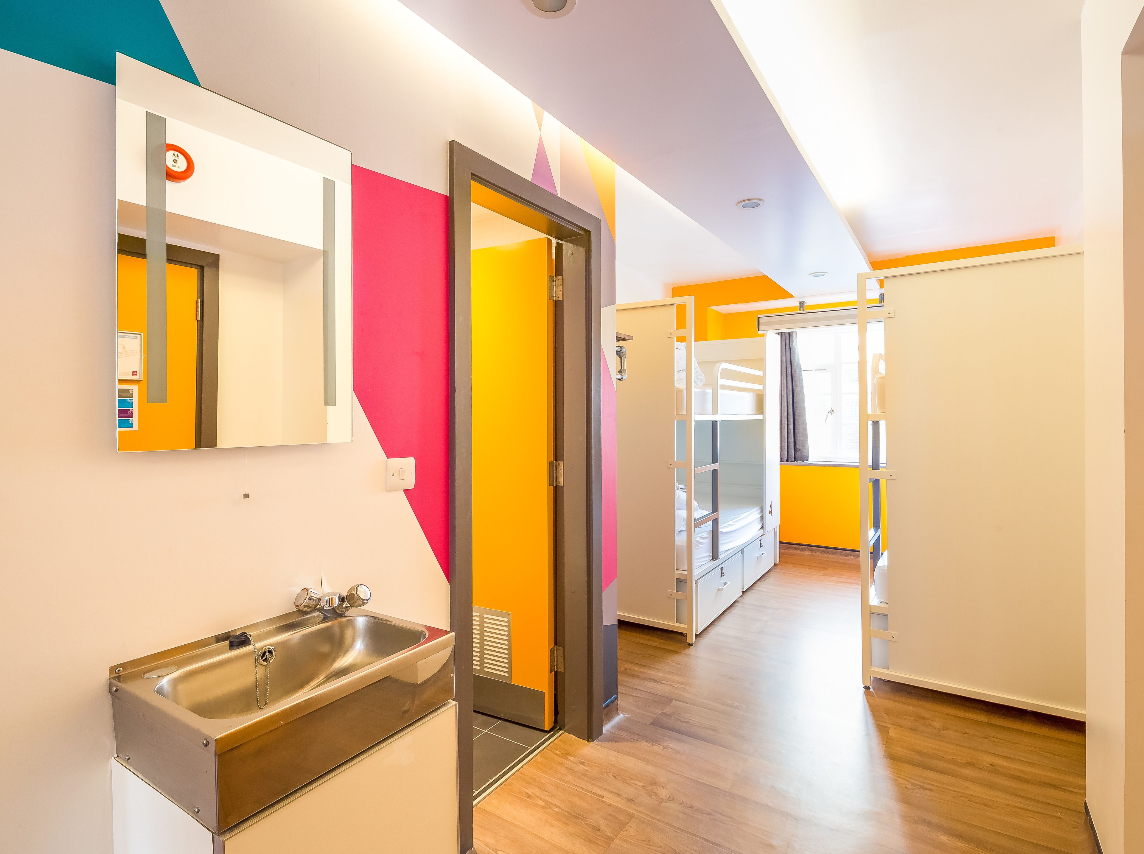 A modern hotel room with a bathroom, a bunk bed, and a view of the city.