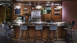 A bar area with a wooden counter, bar stools, and a coffee machine. - Generator London (London)