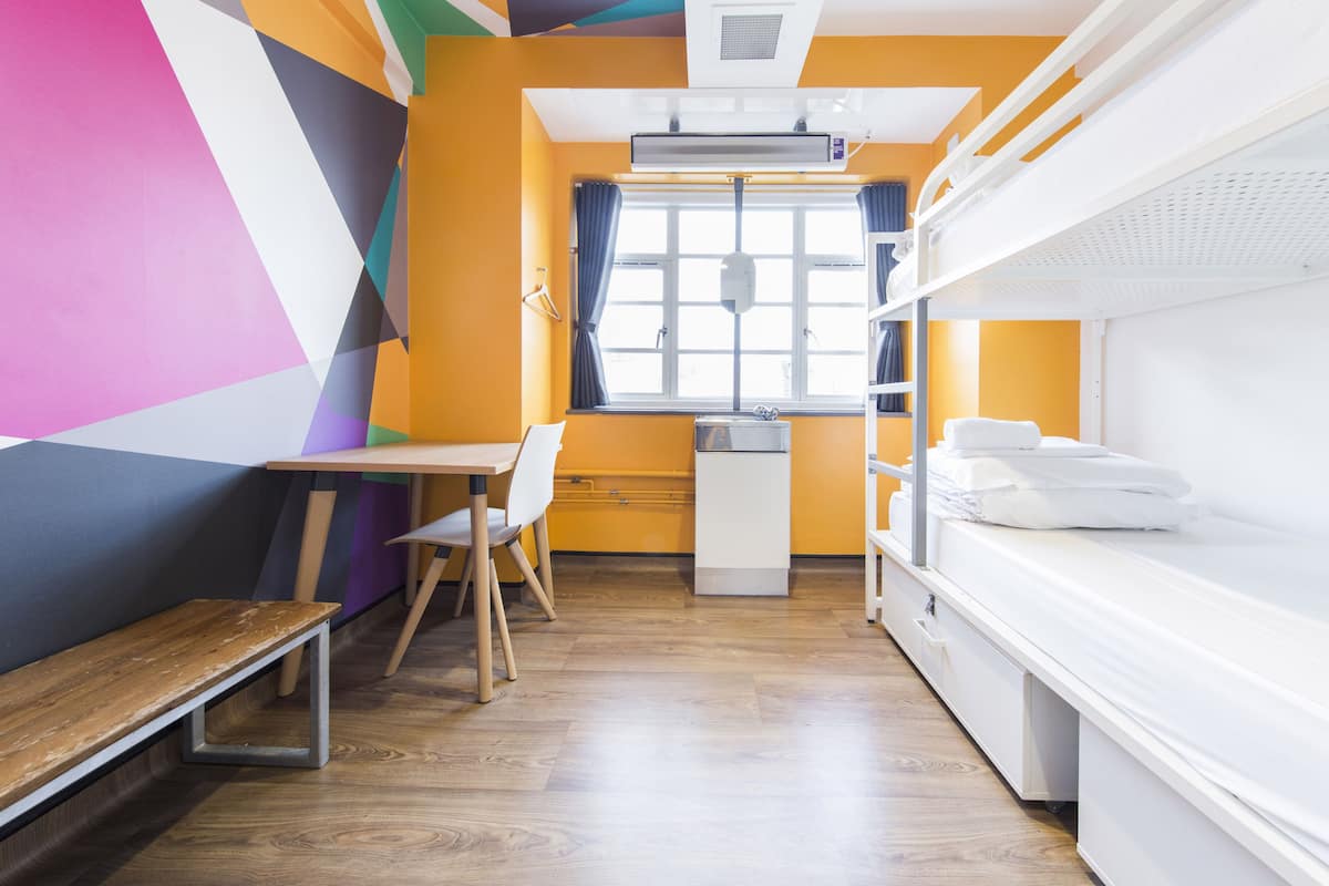 A room with bunk beds, a desk, a chair, and a window with curtains.