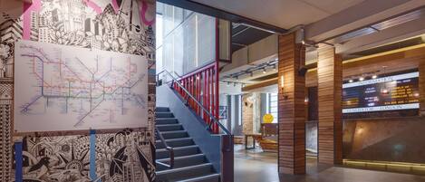 A modern interior with a staircase, a map on the wall, and a digital information board.