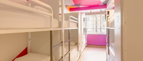 A bunk room with white bunk beds, a wooden floor, and a colorful ceiling design.