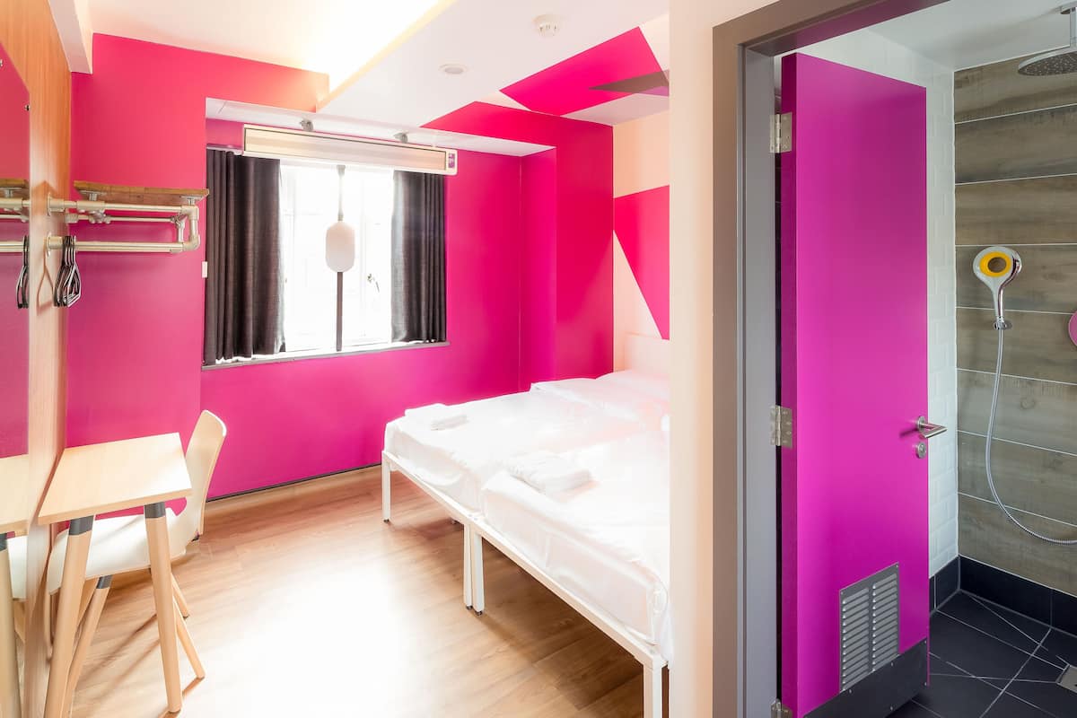 A room with a bed, a desk, and a shower area.