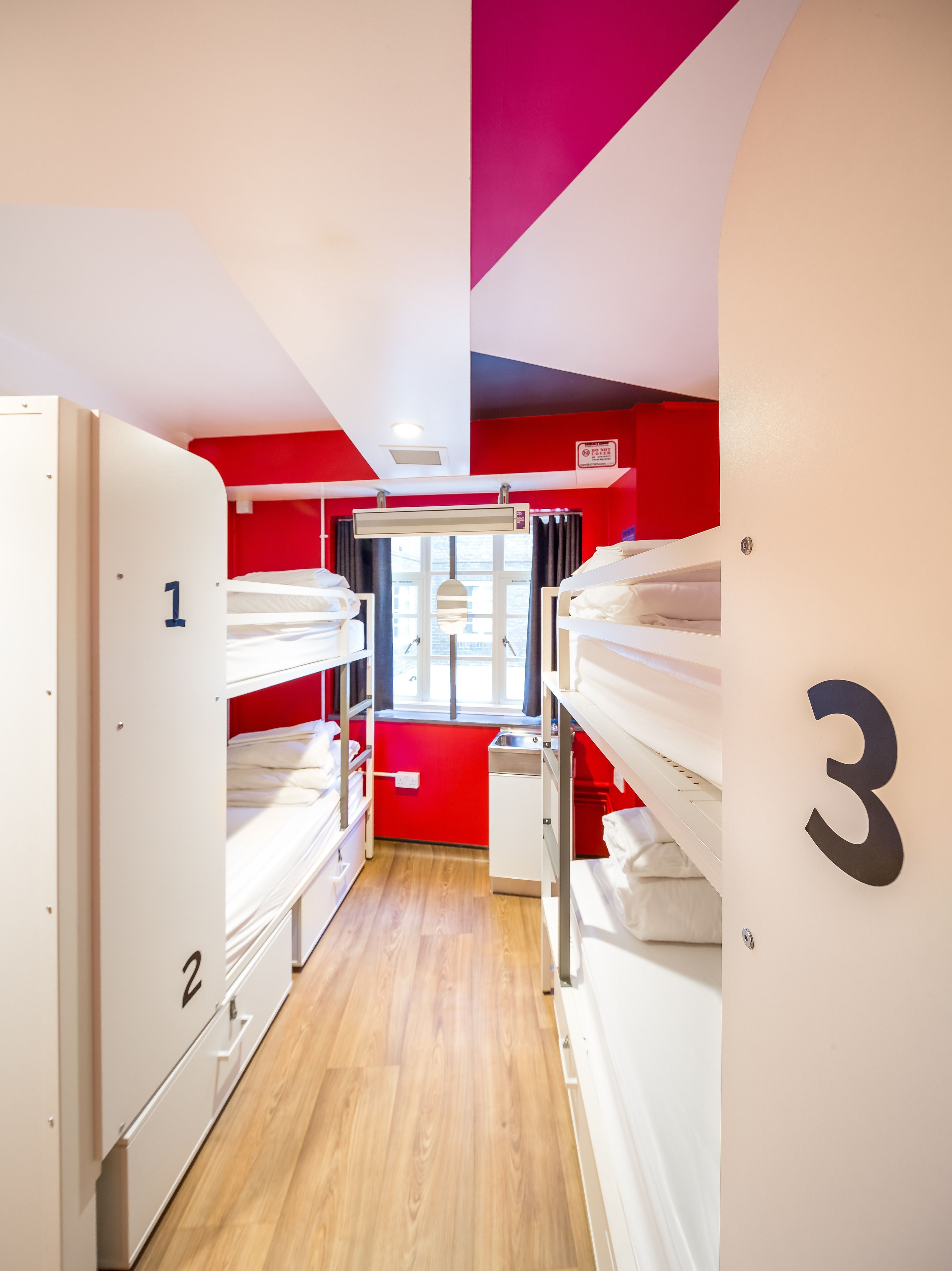 A narrow corridor with bunk beds numbered 1, 2, and 3, leading to a window with curtains.