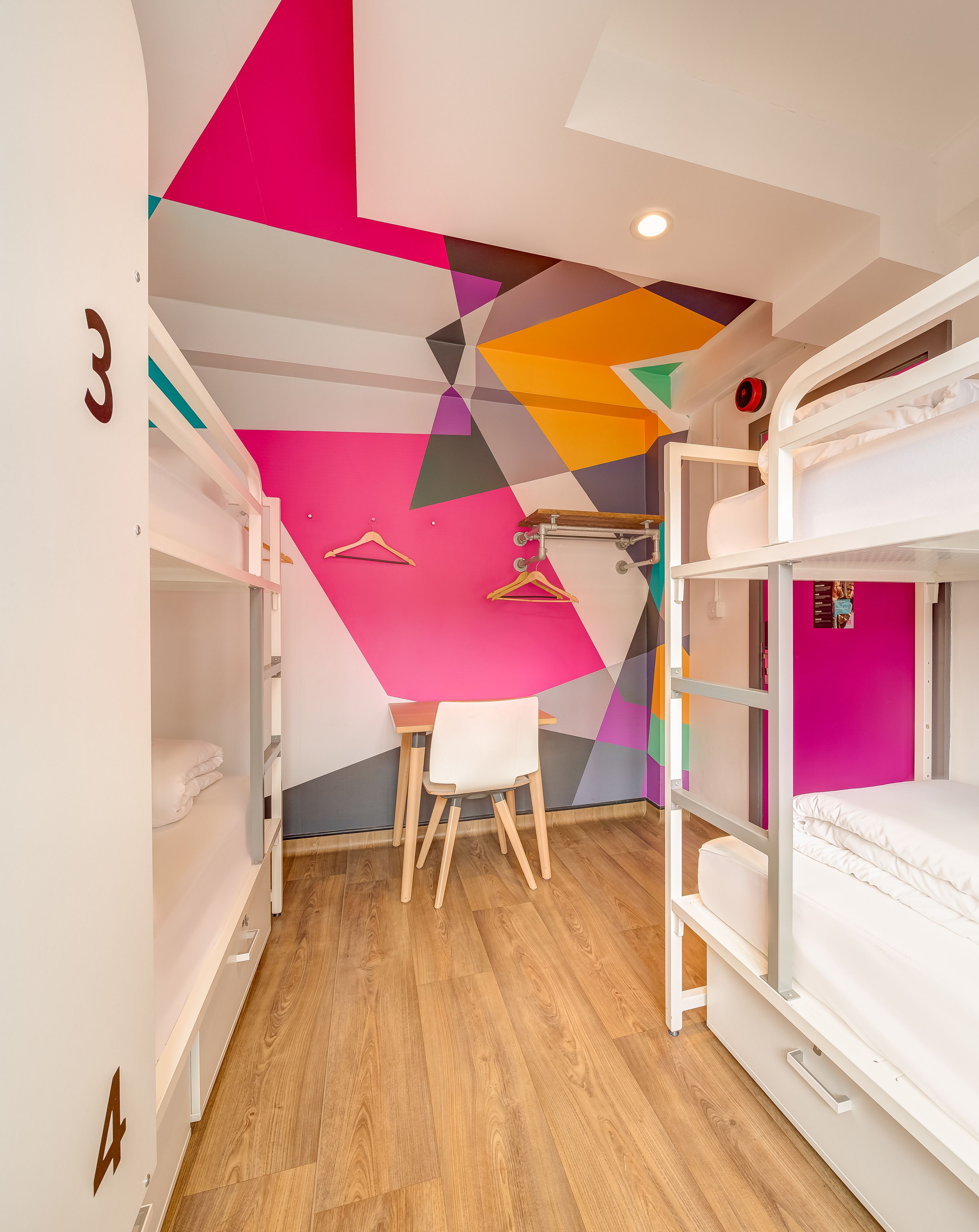 A room with bunk beds, a desk, and a chair.