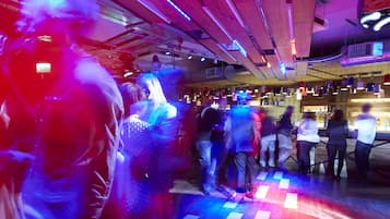 A crowded indoor space with wooden beams and a checkered floor pattern.