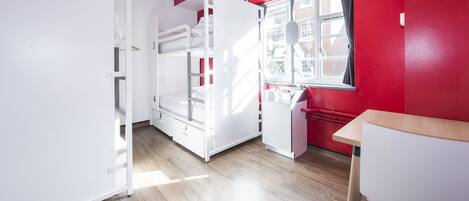 A compact room with bunk beds, a small kitchenette, and a window with a view.