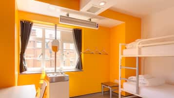 A brightly colored room with a bunk bed, a small table, a chair, and a window with curtains.