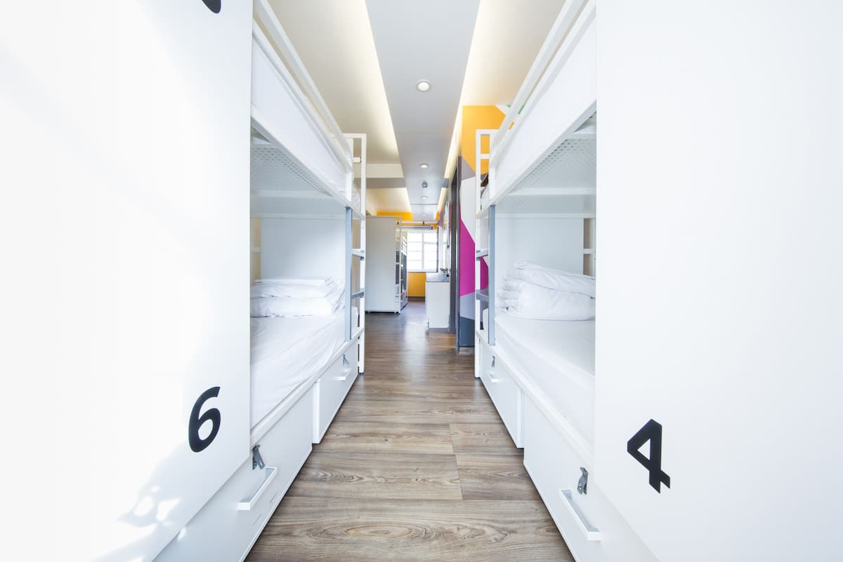 A corridor with bunk beds numbered 4 and 6, wooden flooring, and a bright interior.