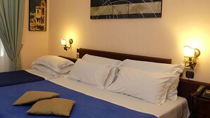 A double bed with two pillows, a bedside table with a lamp, and a painting on the wall. - Toledo Hotel (Naples)