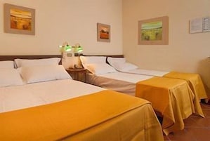 Camera d'albergo con due letti, un comodino e una lampada.