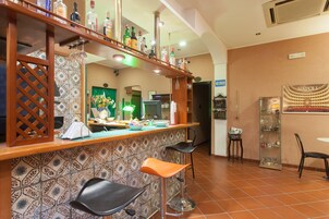 Angolo bar con schienale piastrellato, sgabelli da bar e diverse bottiglie sullo scaffale.