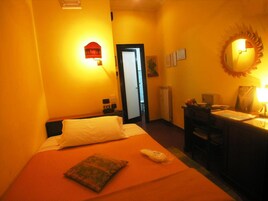 Een hotelkamer met een bed, bureau, stoel, spiegel en deur.
