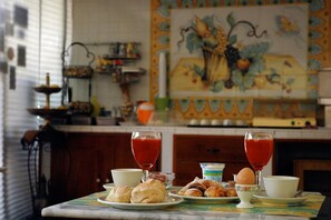 Una mesa de desayuno con croissants, una taza de café, un vaso de jugo rojo y un bol de yogur.