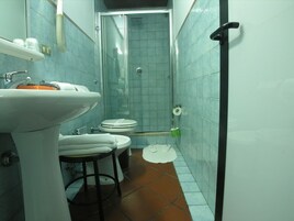 Egy kis méretű fürdőszoba mosdókagylóval, WC-vel és zuhanyzóval.