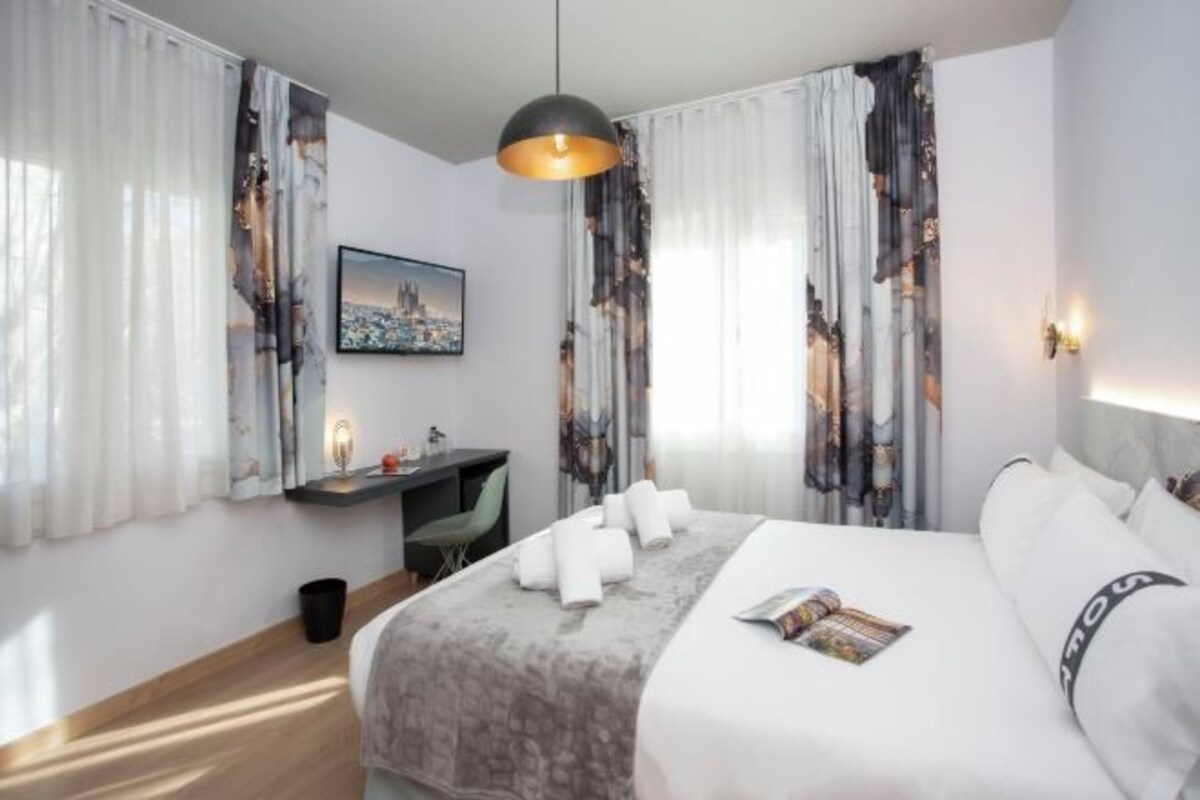 A hotel room with a bed, a desk, and a chair.