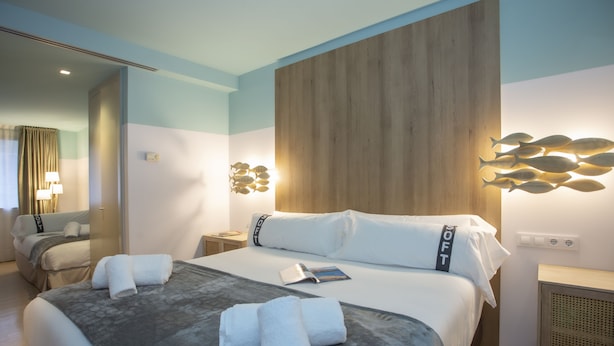 A hotel room with a large bed, a bedside table, a lamp, and a wall-mounted light fixture. - Casual Colours Barcelona Hotel by Casual Hoteles (Barcelona)