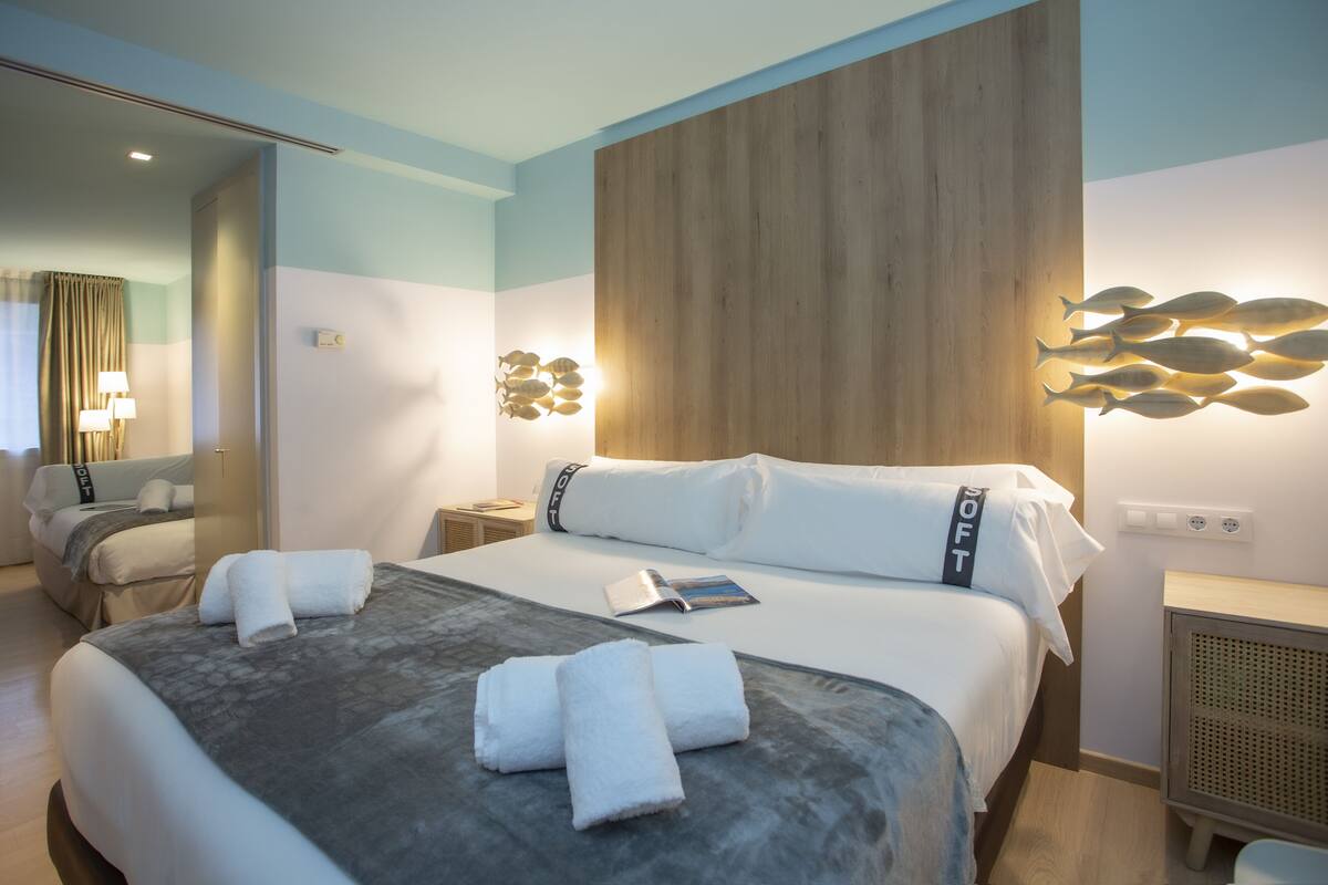 Una habitación de hotel con una cama grande, una mesita de noche, una lámpara y una lámpara de pared.