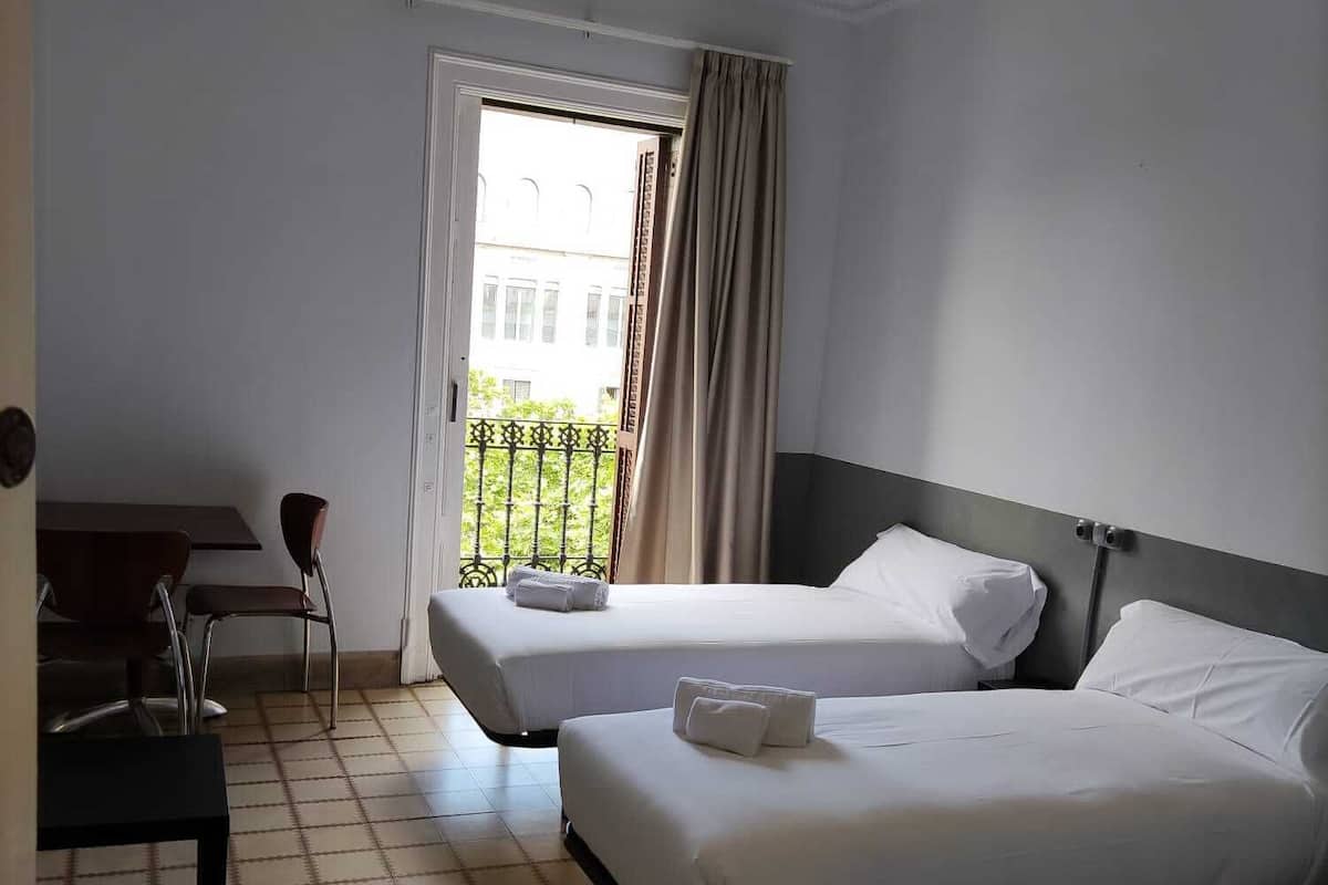 A hotel room with two beds, a desk, and a chair.