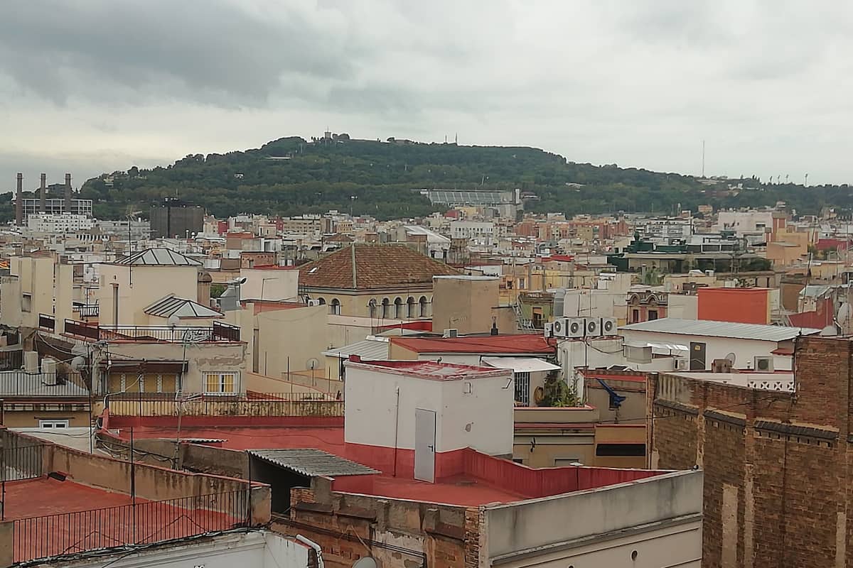 A cityscape with a hill in the background, featuring a mix of residential and commercial buildings.