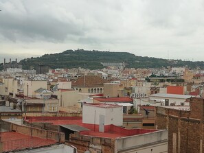A cityscape with a hill in the background, featuring a mix of residential and commercial buildings. - Hotel Monegal (Barcelona)