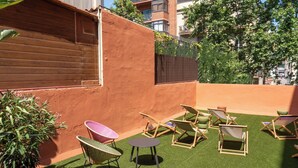 A rooftop terrace with artificial grass, several lounge chairs, and a small table.