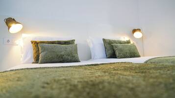 Een bed met twee groene kussens en twee wandlampen.