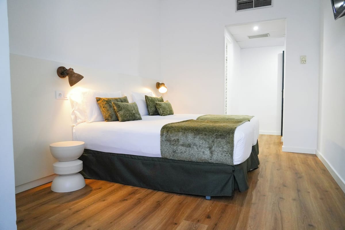 Een netjes ingerichte slaapkamer met een bed, nachtkastjes en wandlampen.