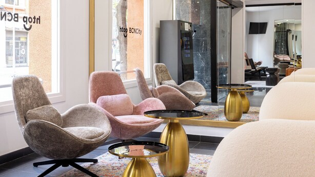 A modern interior with plush seating, a glass partition, and a visible elevator.