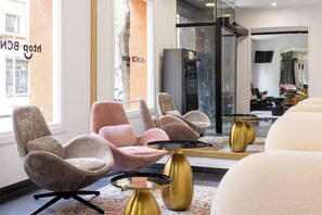 Un intérieur moderne avec des sièges confortables, une cloison en verre et un ascenseur visible.