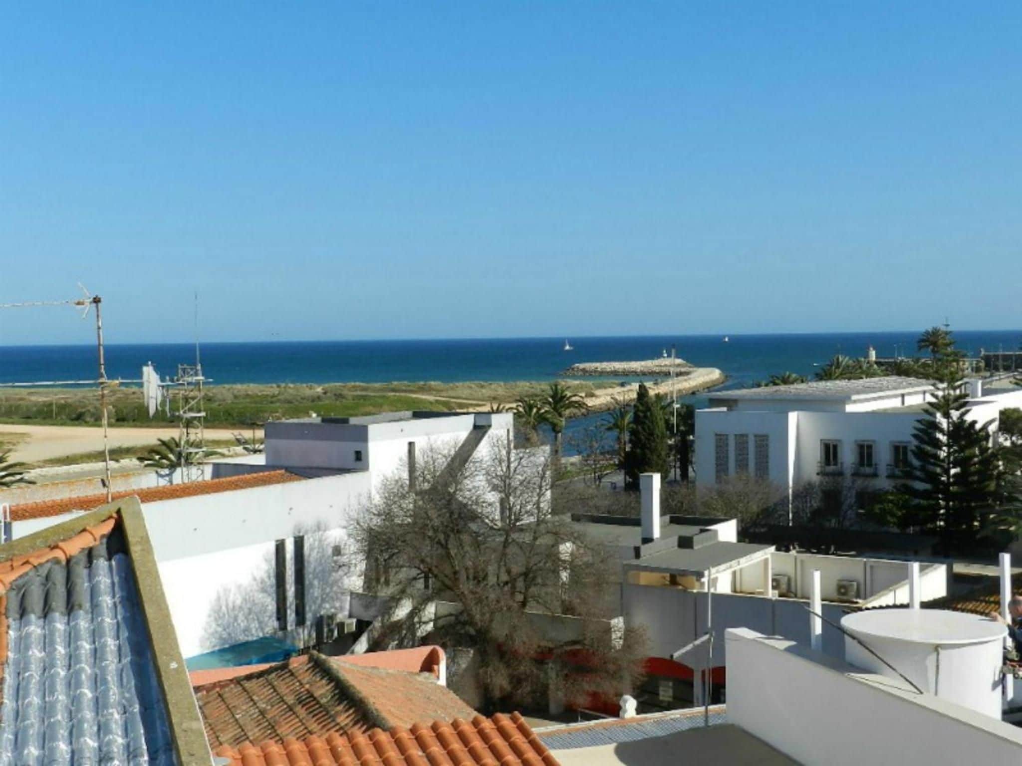 A coastal residential area with buildings, a clear sky, and the sea in the background.