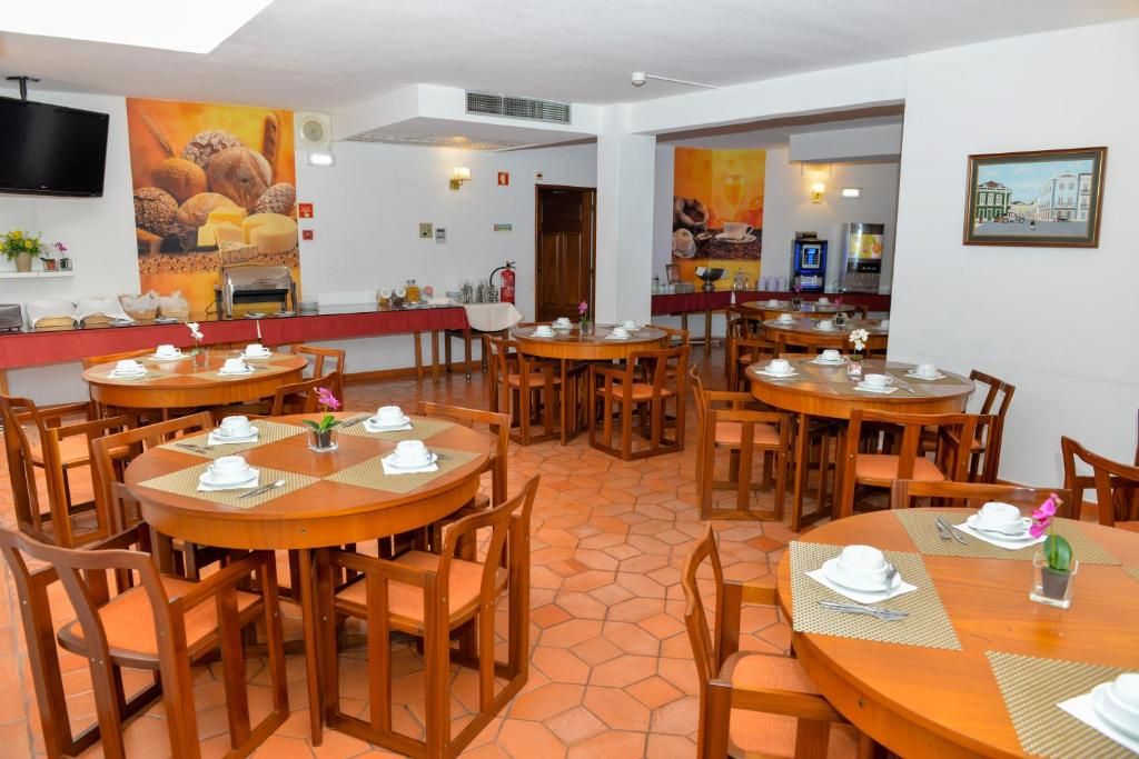Ein Hotel-Speisesaal mit mehreren runden Tischen und Stühlen, komplett mit Tischdeckungen und einem an der Wand befestigten Fernseher.