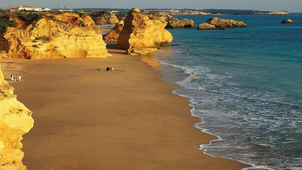 A beach with clear skies, rocky cliffs, and calm sea. - Lagosmar Hotel (Lagos)