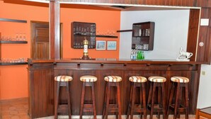 Uma área de bar com taburetes de madeira e prateleiras cheias de copos e garrafas.
