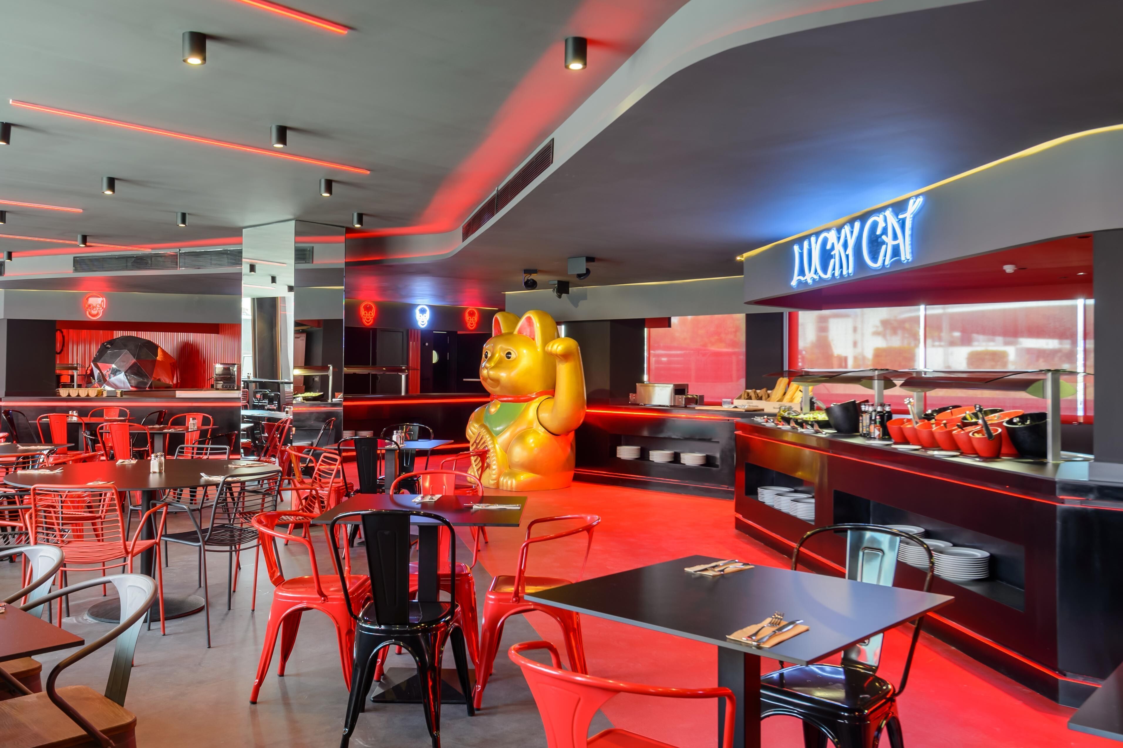 A restaurant with red and black decor, a large golden cat statue, and a neon sign reading "LUCKY CAT".