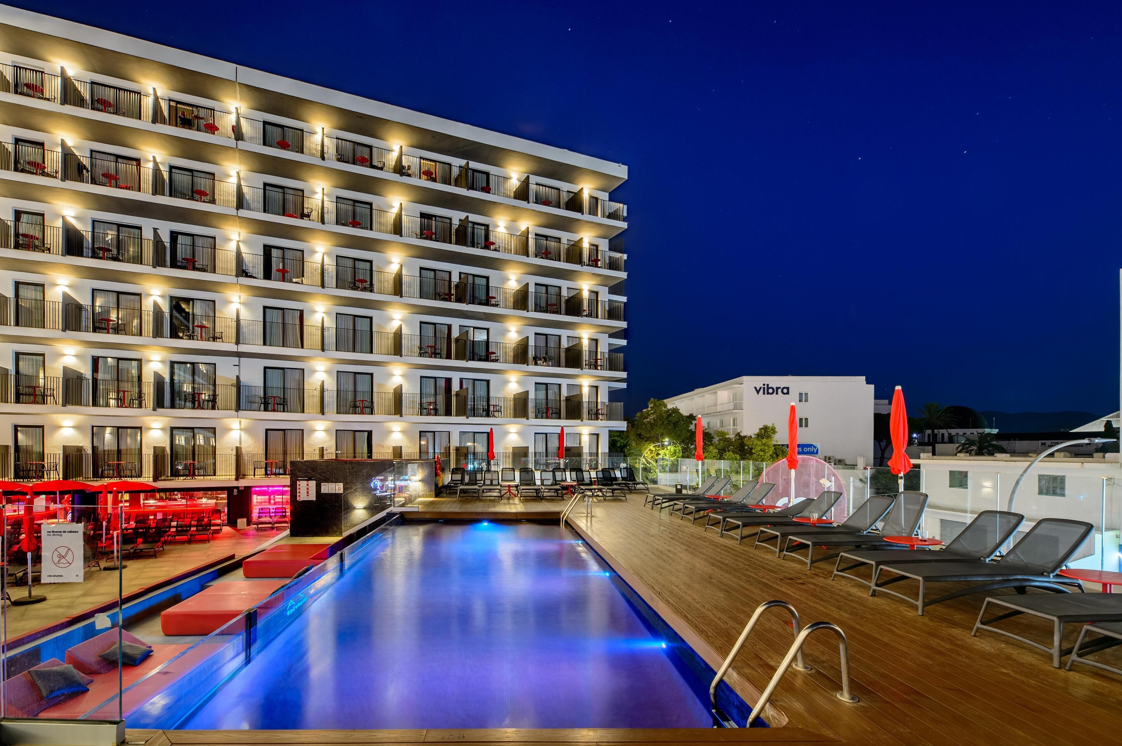 A hotel with a poolside area, multiple balconies, and outdoor seating.