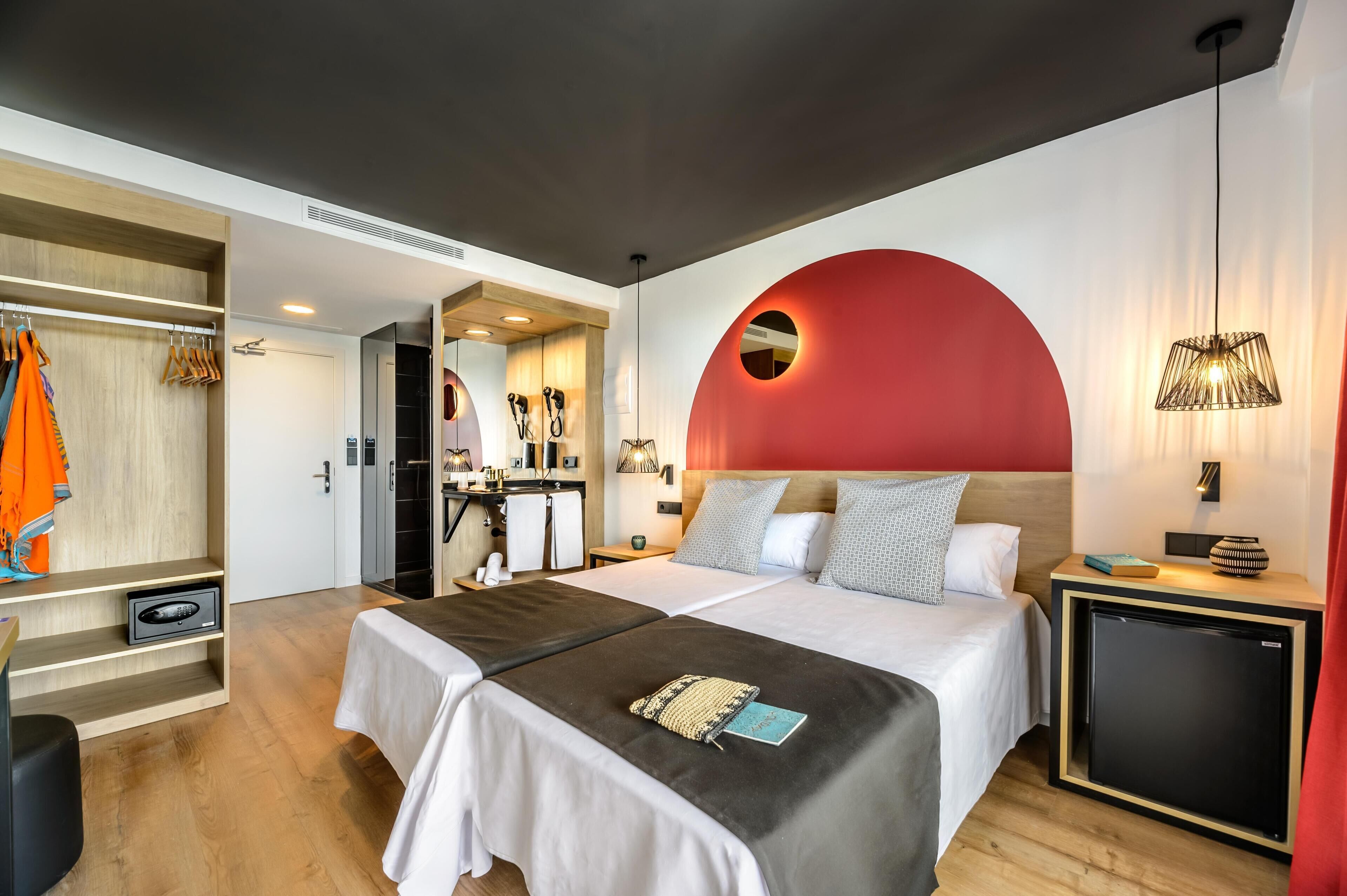 Una habitación de hotel moderna con una cama grande, un armario, un escritorio y un baño.