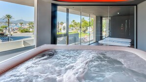 A modern spa room with a hot tub, large windows, and a view of a marina. - Hotel Vibra District - Adults Only (Sant Antoni de Portmany)